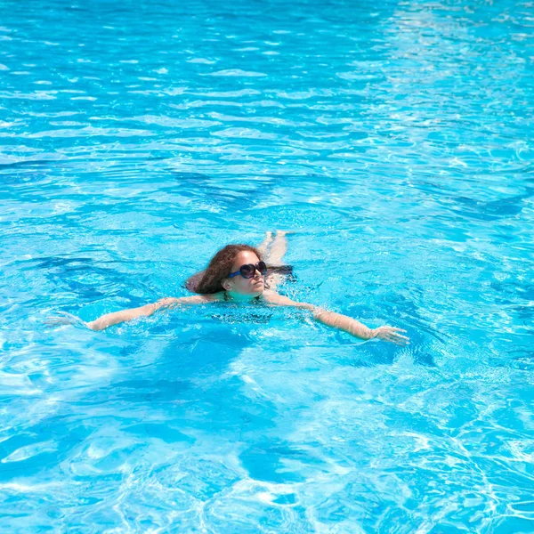 Mooie jonge vrouw genieten van een duik in het zwembad op een zomerdag — Stockfoto