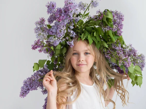 Beautiful childish portrait with a bouquet of lilacs on the head — Stock Photo, Image