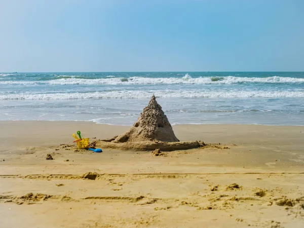 Písečný hrad a dětské hračky na pláži za letního dne — Stock fotografie