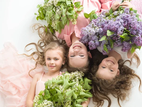 Portrait of three beautiful girls with lilacs in their hands — Stock Photo, Image