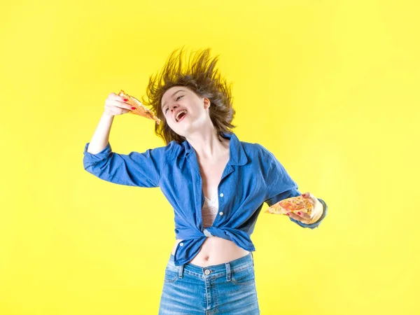 Mooi jong meisje eten pizza op een gele achtergrond — Stockfoto