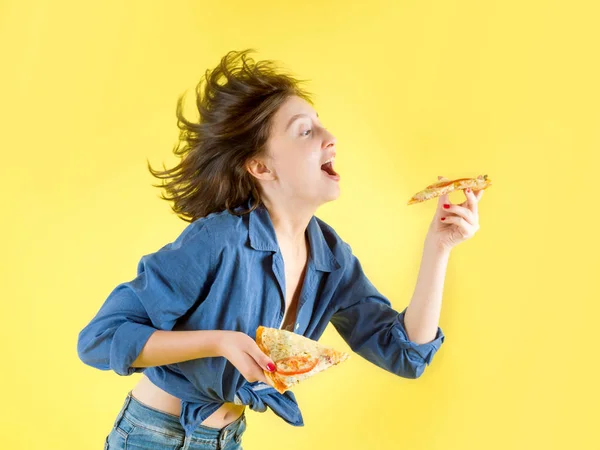 Красива дівчина зі шматочком піци на жовтому фоні — стокове фото