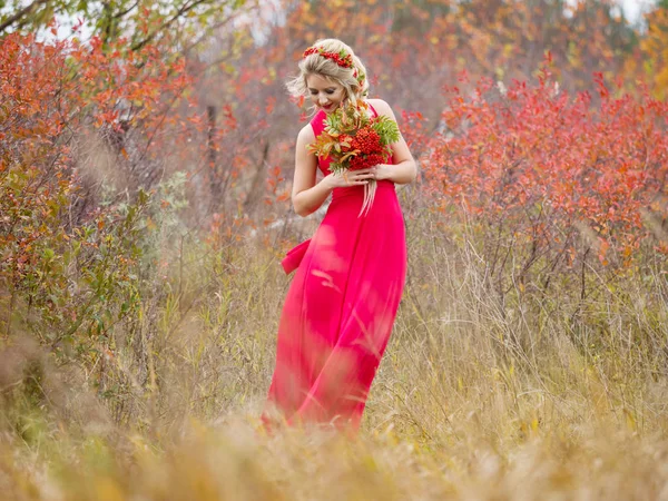 Hermosa chica en un vestido largo rojo con un corte de pelo y con un ramo de rowan otoño en un día de otoño en un campo en la naturaleza —  Fotos de Stock