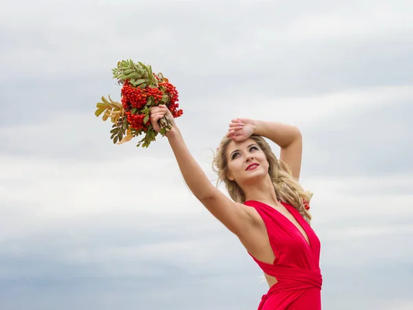 Porträtt av en flicka i en röd klänning dra armarna upp på en bakgrund av blå himmel. Liberty. Höst flicka — Stockfoto