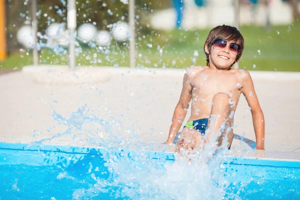 Мальчик брызгает ногами в бассейн на курорте . — стоковое фото