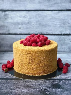 Ahşap zemin üzerinde ahududu olan ballı pasta.