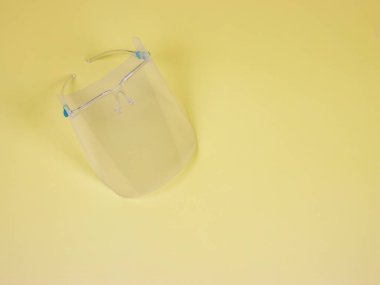Coronavirus veya COVID-19 önleme ve yeni normal yaşam tarzı kavramı. Yüzün üst görünümü kopyalama alanı ile sarı arkaplanda titredi.
