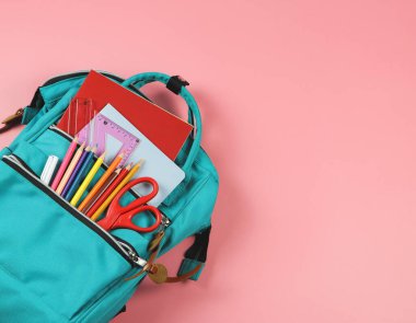 Okul kavramına geri dönelim. Okul malzemeleriyle dolu sırt çantasının üstünde fotokopi alanı olan pembe arka plan..