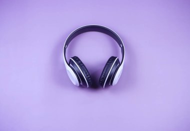 Mor arkaplan, müzik konsepti, minimal biçim üzerine beyaz kulaklığın üst görünümü veya düz yatışı.