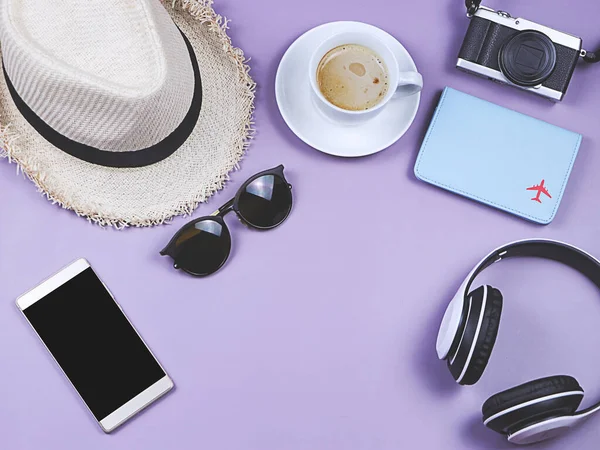 Travel concept. Top view or flat lay of passport cover and  travel accessories with a cup of coffee   on purple background with copy space.