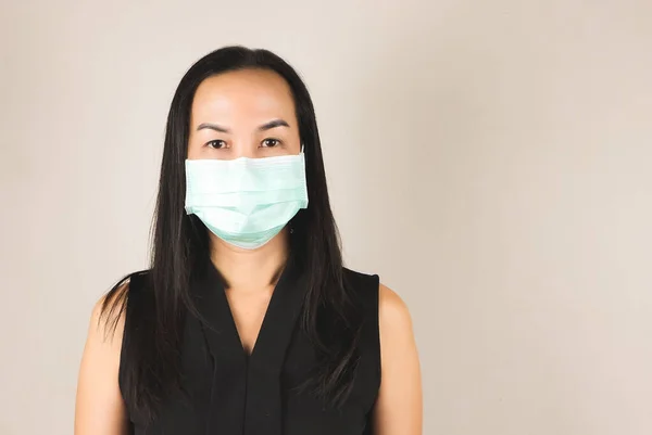 Asian woman wearing hygienic mask on grey background with copy space ,daily protection from corona virus or COVID-19 concept.