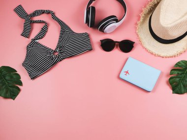 Seyahat ve yaz tatili konsepti, siyah beyaz çizgili bikini mayo, pasaport ve kadın tatil aksesuarları pembe arka planda tropikal canavar yapraklı..
