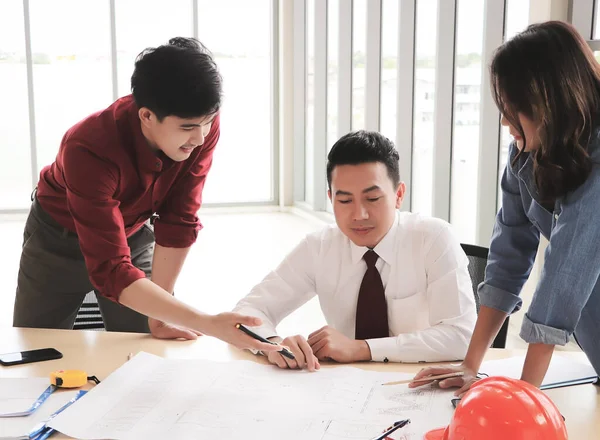 Üç inşaat işçisi, bir kadın mimar ve iki erkek mühendis ofis masasında projeyi tartışıyorlar..