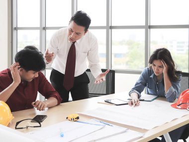 Ofis masasında projeyi tartışan üç inşaat işçisi. İş adamları ve mimarlar hataları yüzünden gergin..