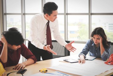 Ofis masasında projeyi tartışan üç inşaat işçisi. İş adamları ve mimarlar hataları yüzünden gergin..