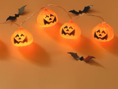 Cadılar Bayramı balkabağı ışıklarının en üst görüntüsü ve fotokopi alanı olan turuncu arka planda siyah kağıt yarasalar. Cadılar Bayramı konsepti.