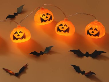 Cadılar Bayramı balkabağı ışıklarının en üst görüntüsü ve fotokopi alanı olan turuncu arka planda siyah kağıt yarasalar. Cadılar Bayramı konsepti.