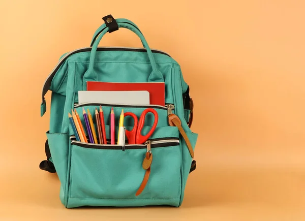 Front view  of  backpack with school supplies   on orange background with copy space.Education and  back  to school  concept.