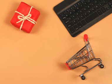 Üst ya da düz alışveriş arabası yatağı, bilgisayar klavyesi ve kırmızı hediye kutusu üzerinde fotokopi alanı. Noel hediyesi ve online alışveriş konsepti.