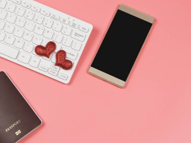 Bilgisayar klavyesindeki kırmızı parıltılı kalbin üst görüntüsü, cep telefonu ve pembe arka plandaki pasaport fotokopi alanı, uzun mesafe aşkı ve online randevu kavramı.
