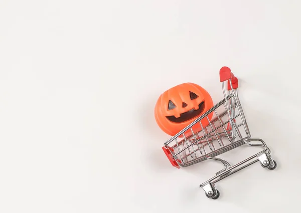 Top view or flat lay of  Halloween pumpkin on shopping cart  on white background with copy space. Halloween holiday concept.