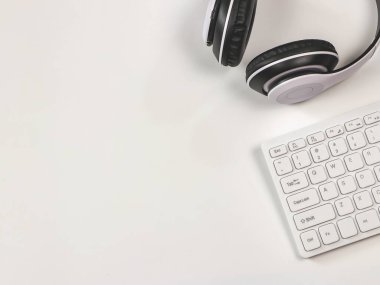 Üst görünüm veya Düz kulaklık ve beyaz arka planda kopyalama alanı olan beyaz bilgisayar klavyesi. Çalışma ve teknoloji konsepti.