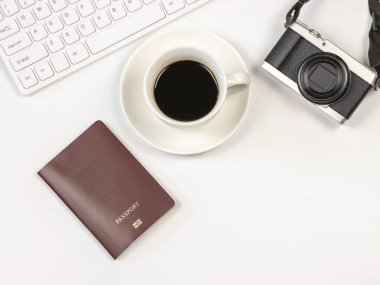 Üst ya da düz kahve fincanı, bilgisayar klavyesi, kamera ve pasaport beyaz arka planda. Seyahat kavramı.