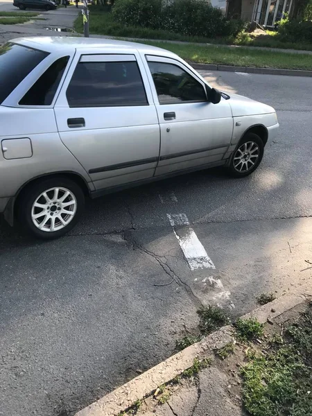 Gümüş renkli araba şehrin caddesi boyunca gidiyor..