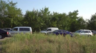 Trafik sıkışıklığı olan yoldan arabalar geçer ve odalar gökyüzüne ve ağaçlara karşı çimenleri kaplar.