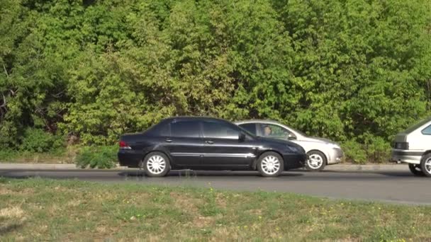 Auto passare lentamente sulla strada al mattino ingorgo davanti ai ponti della città sullo sfondo di fogliame verde — Video Stock