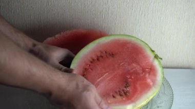Adam lezzetli olgun bir karpuzu bıçakla iki parçaya ayırıp yakın plan çekimde gösteriyor.