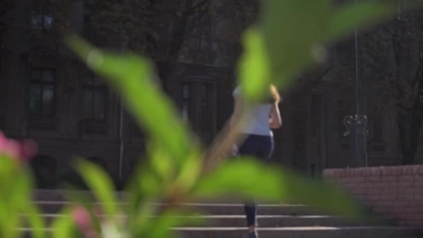 Cabang dengan bunga dan siluet kabur dari seorang gadis berjalan menaiki tangga di jalan kota — Stok Video