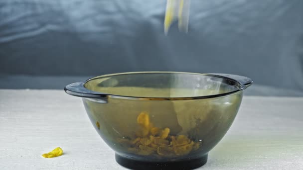 Pria menuangkan dalam piring kaca transparan kosong cornflakes di pagi hari untuk sarapan yang tersisa hanya untuk menambahkan susu — Stok Video