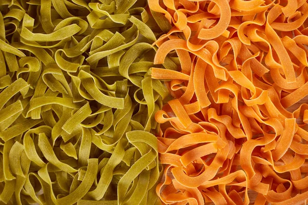 Fondo de pasta verde y naranja seca sin cocer — Foto de Stock