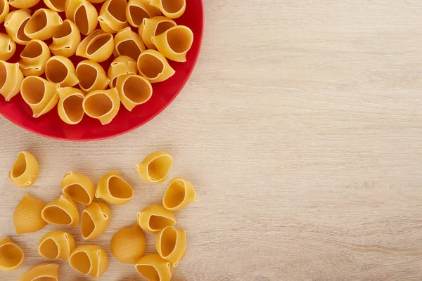 Pasta cruda en un plato rojo, vista superior, espacio para copiar — Foto de Stock