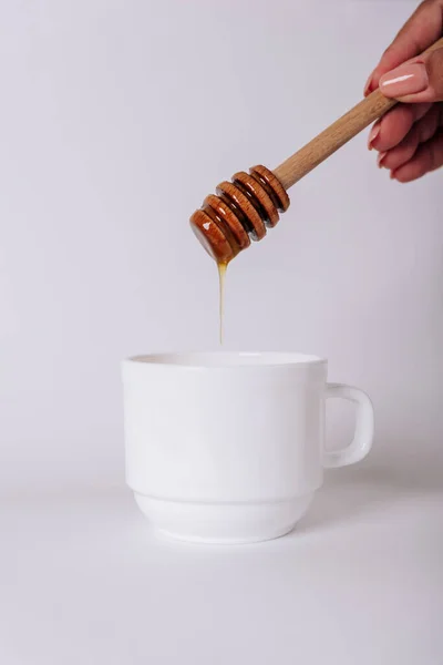 La mano de las niñas sostiene un Honey Dipper en una taza blanca — Foto de Stock