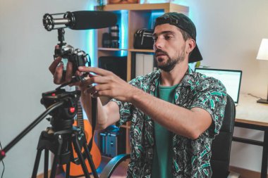 Sakallı bir erkek fotoğrafçı video çekmek için kamera ekipmanını ayarlıyor. Nüfuz Edici çevrimiçi video hazırlıyor. İnanılmaz çalışma alanı.