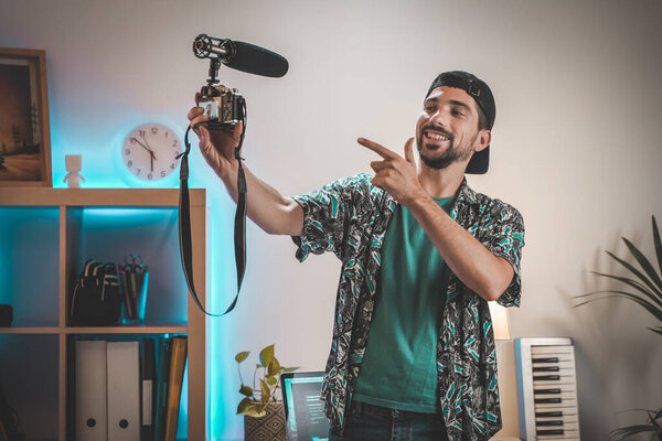 За сценой снят молодой человек, влияющий на создание видео. Очень красивый мужчина с бородой снимает видео для соцсетей, разговаривающих непосредственно с камерой. Удивительное рабочее пространство Влиятеля.