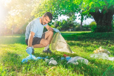 Coronavirus. Koronavirüs salgını sırasında yeşil çimlerin üzerinde duran mavi lastik eldivenler ve yüz maskeleri alan bir adam. Çevre kirliliği. Kullanılmış. Çöp.. 