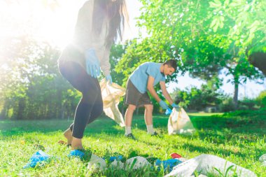 Coronavirus. Çift yeşil çimlerin üzerinde yatan koronavirüs salgını sırasında mavi lastik eldiven ve yüz maskesi alıyor. Çevre kirliliği. Çöp.. 