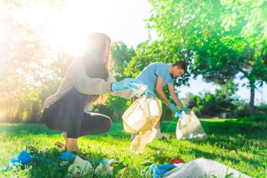 Coronavirus. Çift yeşil çimlerin üzerinde yatan koronavirüs salgını sırasında mavi lastik eldiven ve yüz maskesi alıyor. Çevre kirliliği. Çöp.. 