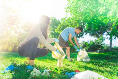 Coronavirus. Çift yeşil çimlerin üzerinde yatan koronavirüs salgını sırasında mavi lastik eldiven ve yüz maskesi alıyor. Çevre kirliliği. Çöp.. 