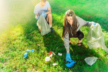 Coronavirus. Çift yeşil çimlerin üzerinde yatan koronavirüs salgını sırasında mavi lastik eldiven ve yüz maskesi alıyor. Çevre kirliliği. Çöp.. 