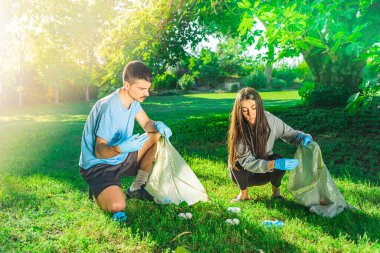 Coronavirus. Çift yeşil çimlerin üzerinde yatan koronavirüs salgını sırasında mavi lastik eldiven ve yüz maskesi alıyor. Çevre kirliliği. Çöp.. 