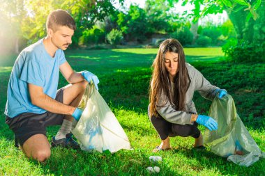 Coronavirus. Çift yeşil çimlerin üzerinde yatan koronavirüs salgını sırasında mavi lastik eldiven ve yüz maskesi alıyor. Çevre kirliliği. Çöp.. 
