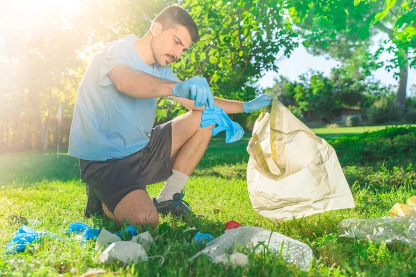 Coronavirus. Koronavirüs salgını sırasında yeşil çimlerin üzerinde duran mavi lastik eldivenler ve yüz maskeleri alan bir adam. Çevre kirliliği. Kullanılmış. Çöp.. 