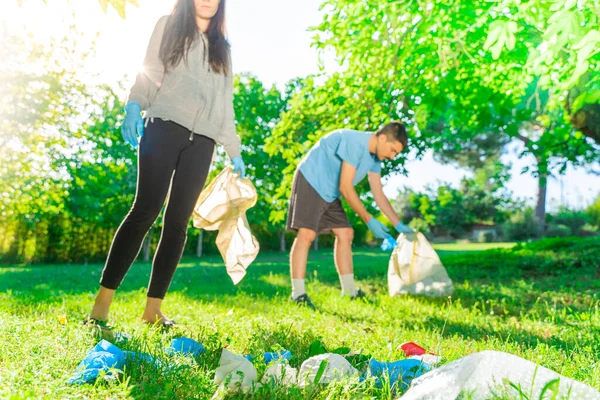 Coronavirus. Çift yeşil çimlerin üzerinde yatan koronavirüs salgını sırasında mavi lastik eldiven ve yüz maskesi alıyor. Çevre kirliliği. Çöp.. 