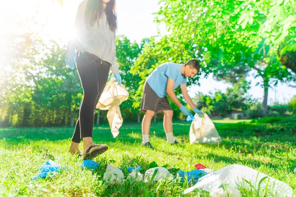 Coronavirus. Couple picking up blue rubber gloves and face masks during coronavirus epidemic lying on green grass. Environment contamination. Garbage.