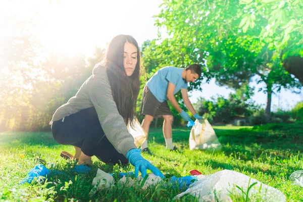 Coronavirus 科罗纳韦病毒流行期间 夫妇们在绿草上拾起蓝色的橡胶手套和面罩 环境污染 — 图库照片