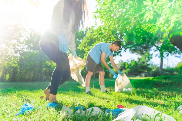 Coronavirus. Çift yeşil çimlerin üzerinde yatan koronavirüs salgını sırasında mavi lastik eldiven ve yüz maskesi alıyor. Çevre kirliliği. Çöp.. 